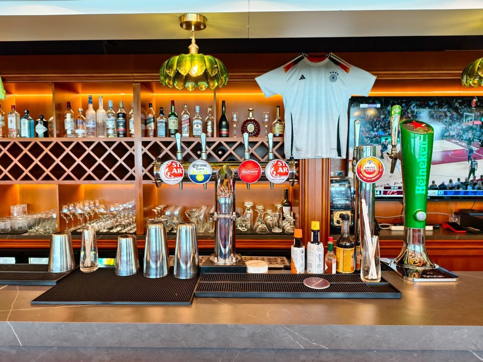 A bar area with multiple beer taps, a variety of bottles, and a sports jersey on display.