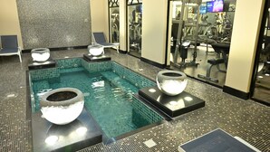 Un área de spa con piscina, equipo de ejercicios y sillones de relajación.