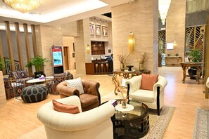 A spacious lobby with leather sofas, a reception desk, and a modern chandelier. - Savoy Grande Hotel and Spa (Manama)