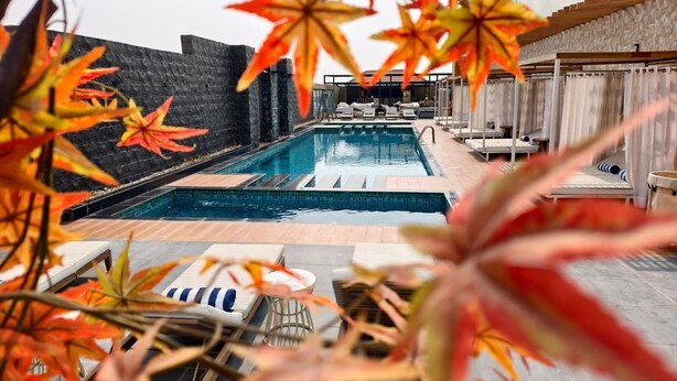 Una piscina con sillas de descanso y un muro de piedra.