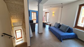 Un apartamento moderno con un sofá azul, una zona de comedor y una cocina.