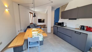 Una cocina moderna con armarios grises, una mesa de comedor de madera y un televisor montado en la pared.