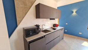 Una cocina compacta con microondas, cafetera y lavamanos.