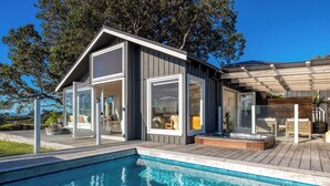 Een modern huis met zwembad, grote ramen en een terras.