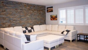 A modern living room with a sectional sofa, a small side table, and a brick accent wall.