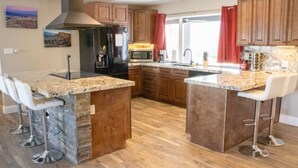 A modern kitchen with granite countertops, wooden cabinets, and a central island with bar stools.