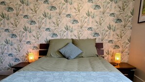 Ein Bett mit einem gemusterten Überwurf, zwei Kissen und zwei Nachttischlampen.