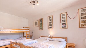 Een slaapzaal met stapelbedden, een klein tafeltje en ingelijste foto's aan de muur.