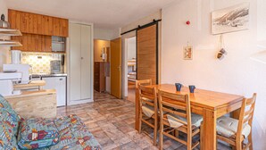 Een knus woongedeelte met een kitchenette, een eethoek en een slaapbank.
