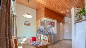 Una cocina moderna con techo de madera, electrodomésticos de acero inoxidable y un comedor con mesa y sillas.