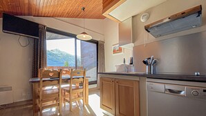Una cocina con armarios de madera, lavavajillas integrado y ventana con vistas a la montaña.