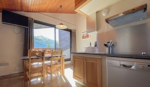 A kitchen with wooden cabinets, a stove, and a window with a mountain view.