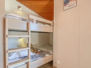 Ein Etagenbett mit einer Leiter, einem Teddybären und einem Poster an der Wand.