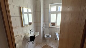 Kylpyhuone, jossa on wc, pesuallas, peili ja ikkuna.
