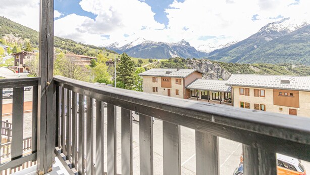Un balcon donnant sur une chaîne de montagnes et des bâtiments.