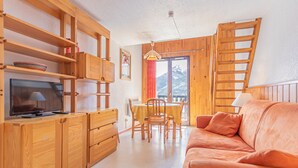 Une pièce confortable, dotée de meubles en bois, d’un téléviseur, d’une table à manger avec des chaises et d’un canapé.