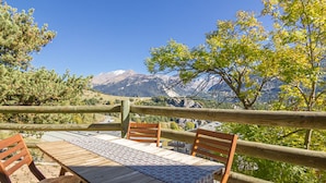 A wooden table with chairs, a patterned tablecloth, and a mountain view. - Aussois: 2-room apartment, terrace, sleeps 6, pets allowed, WIFI (Aussois)