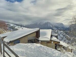 Ein schneebedecktes Bergresort mit Chalets, einer Seilbahn und Blick auf die umliegenden Berge.