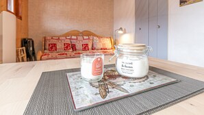 Una habitación acogedora con cabecera de madera, un sofá, una pequeña mesa con velas y un plato decorativo, y una pared con un póster.