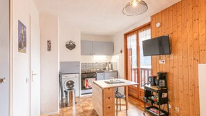Una cocina compacta con lavadora, cafetera y televisor montado en la pared.