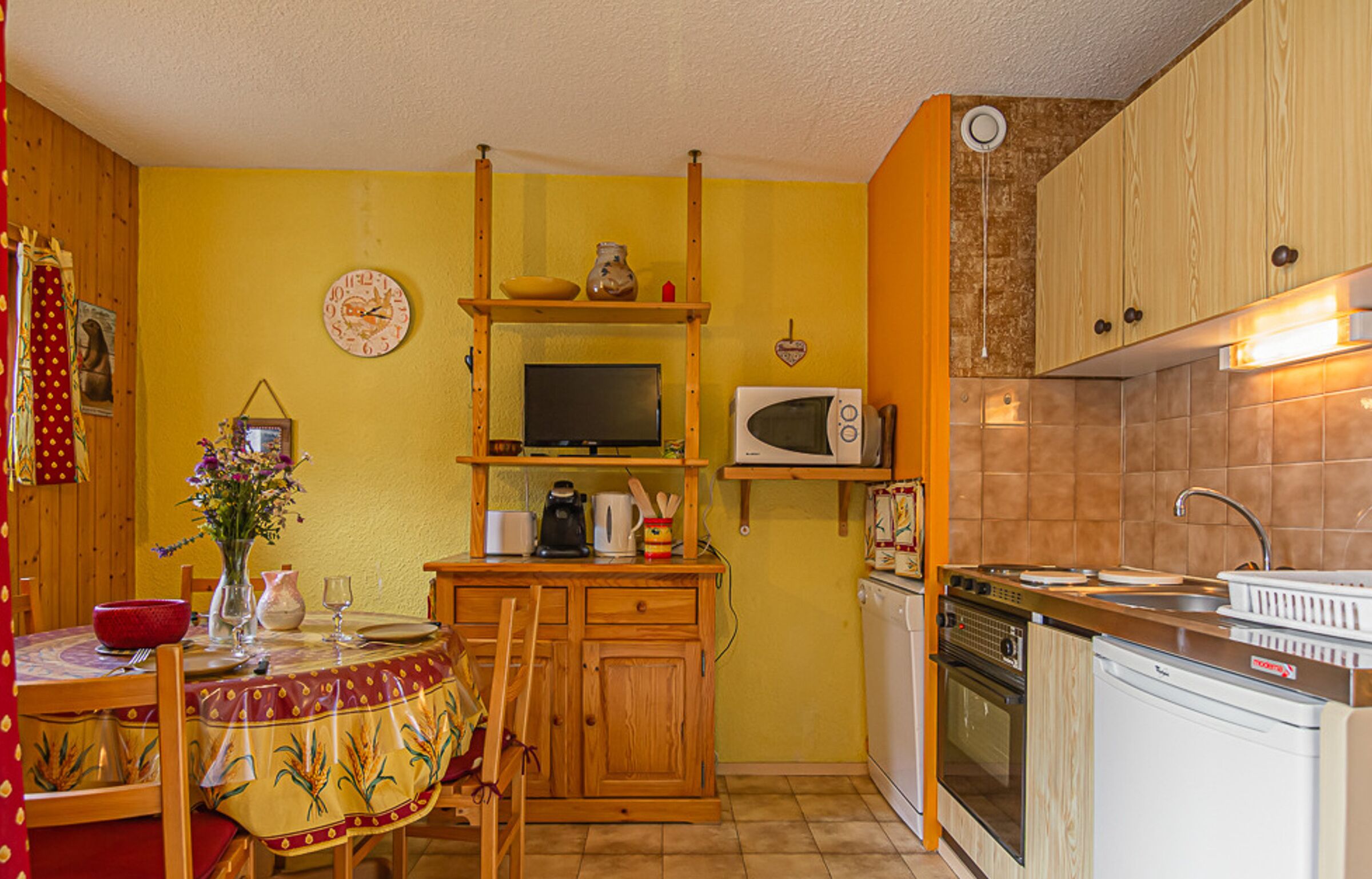 A compact kitchen with wooden cabinets, a microwave, a stove, and a sink.