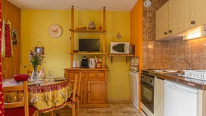 Une cuisine de taille réduite, dotée de meubles en bois, d’un four à micro-ondes, d’une cuisinière et d’un évier.
