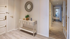 A hallway with a white console table, a mirror, and a wicker basket. - Beautiful sea-view apartment with WiFi and parking in Palamós (Palamós)