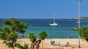 A coastal scene with a sailboat, beach, and a sign for Integral Finques. - Beautiful sea-view apartment with WiFi and parking in Palamós (Palamós)