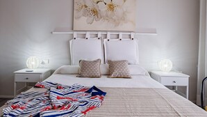 A bedroom with a bed, two nightstands, a decorative wall piece, and a blanket. - Beautiful sea-view apartment with WiFi and parking in Palamós (Palamós)