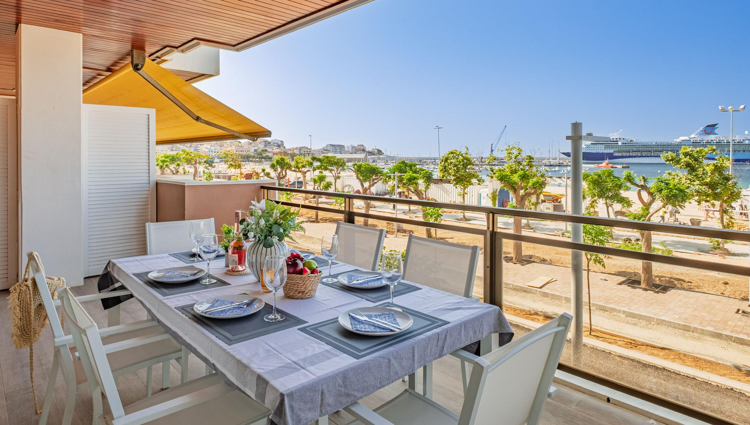 Een eethoek met een tafel voor vier personen, met uitzicht op een jachthaven en strand.