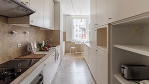 Una cocina estrecha con gabinetes blancos, una estufa negra y una ventana que proporciona luz natural.