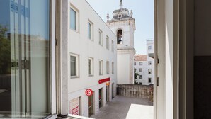Una calle estrecha con una torre de campanas al fondo.