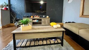A living room with a flat-screen TV, a wooden coffee table, a sofa, decorative pumpkins, and a wall with a star pattern. - Charming, Private , 3BR, 1Bath Main Floor Close to all action Stadiums & Sports (Minneapolis)