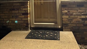 A wooden door with a glass panel, a stone wall, a metal doorbell, and a small electronic device on the wall. - Charming, Private , 3BR, 1Bath Main Floor Close to all action Stadiums & Sports (Minneapolis)