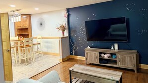A living room with a TV, wooden furniture, a dining area, and a decorative wall. - Charming, Private , 3BR, 1Bath Main Floor Close to all action Stadiums & Sports (Minneapolis)