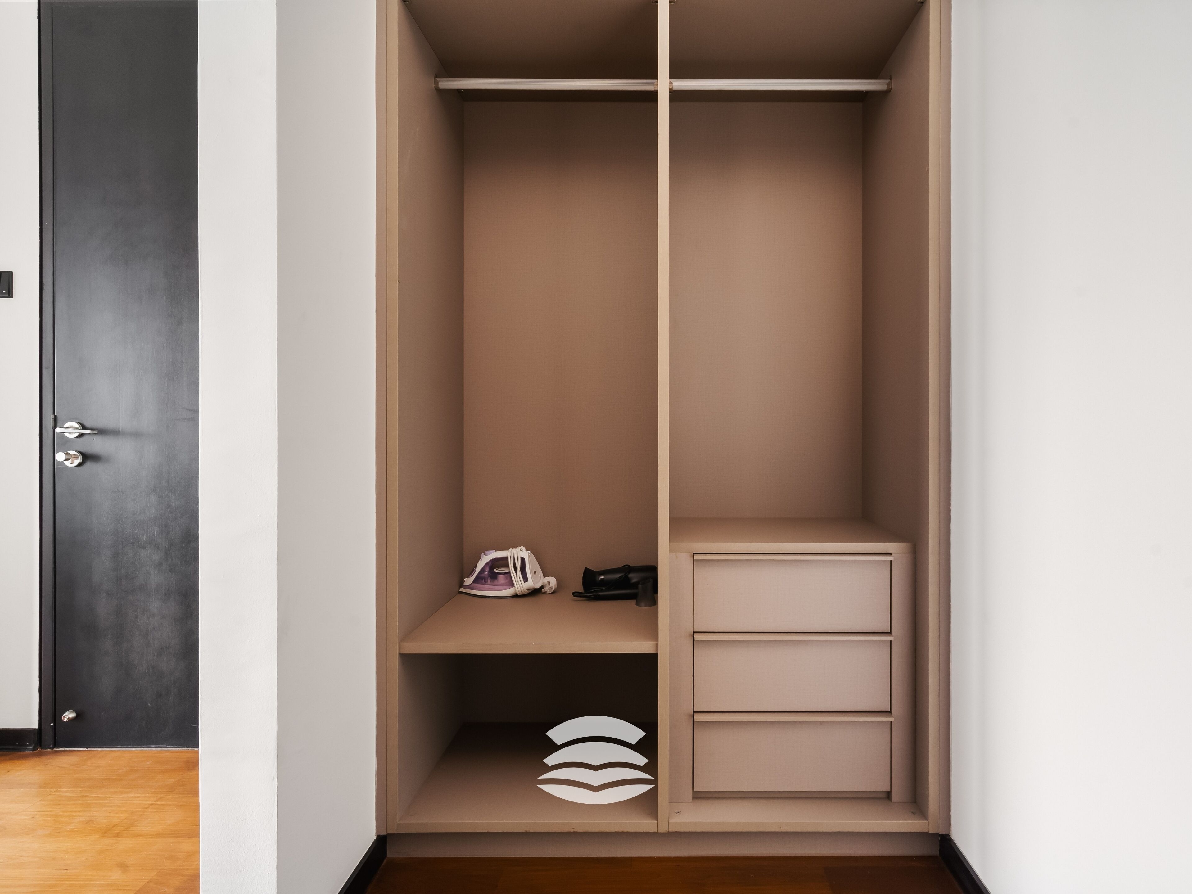 Un armario abierto con una puerta oscura, un zapatero colgante y un mueble de almacenamiento con cajones.