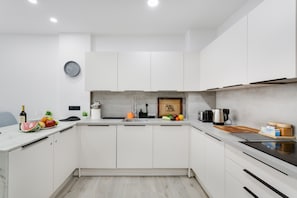 Uma cozinha moderna com armários brancos, pia e diversos eletrodomésticos.
