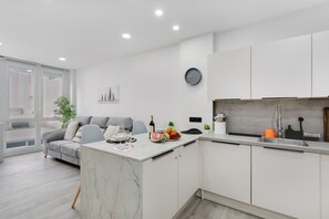 Una cocina moderna con gabinetes blancos, una isla de mármol y un lavamanos empotrado.