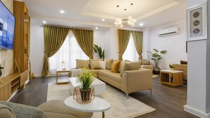 Een moderne woonkamer met een beige bank, een witte salontafel en een aan de muur bevestigde televisie.