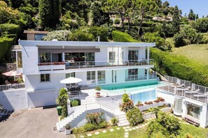 A modern two-story house with a swimming pool, a balcony, and a well-maintained garden.
