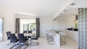 A modern kitchen with a glass-top dining table, black chairs, and a bar area. - Villa Loupa - Calm and Harmony (La Colle-sur-Loup)