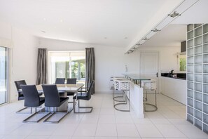 Una cocina moderna con una mesa de comedor de vidrio, sillas negras y una barra.
