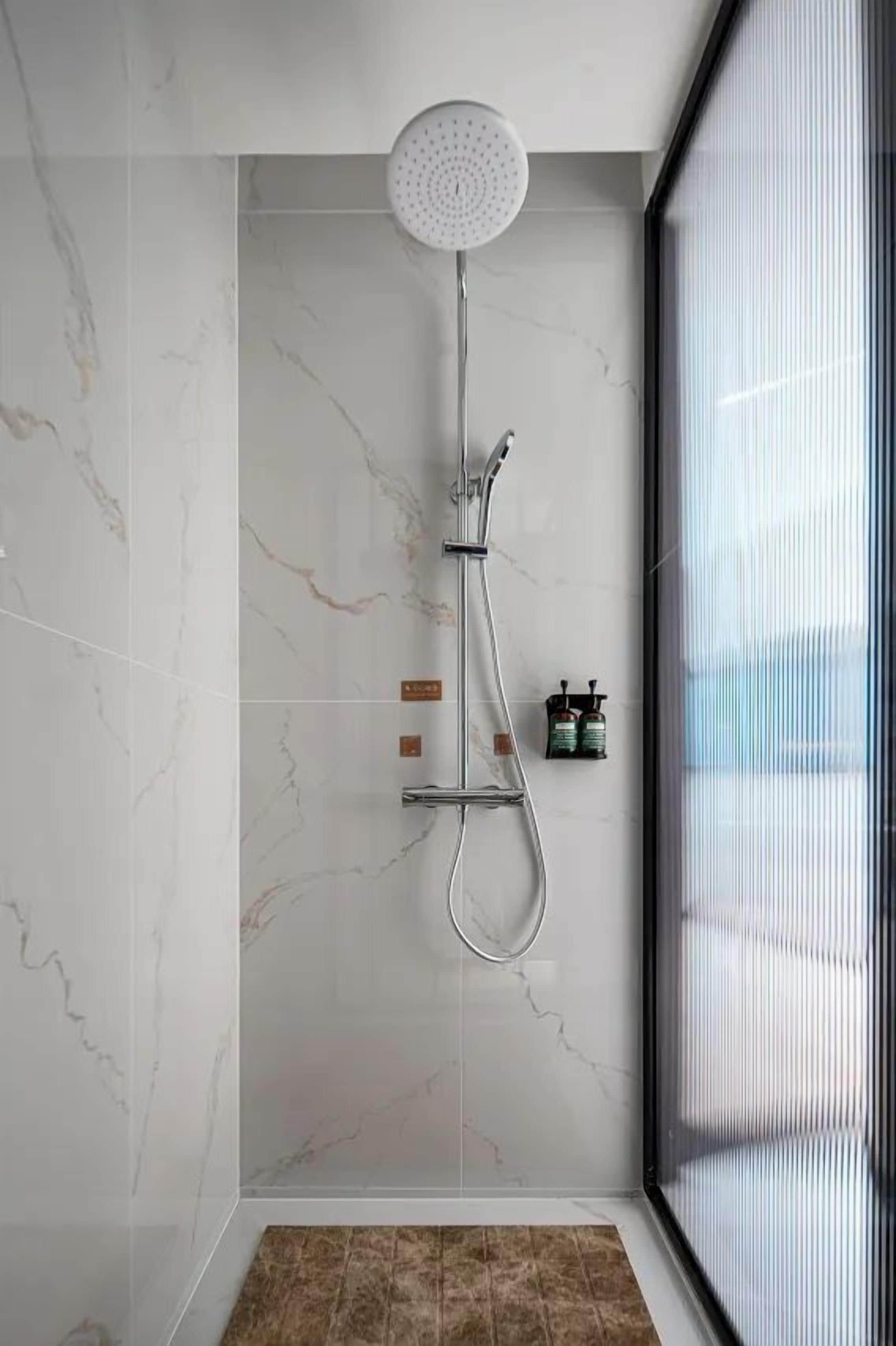 Ducha moderna con cabezal de ducha manual, un accesorio de ducha portátil y un grifo montado en la pared.
