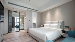 Una habitación de hotel moderna con una cama grande, una mesita de noche, una silla y un vestidor.
