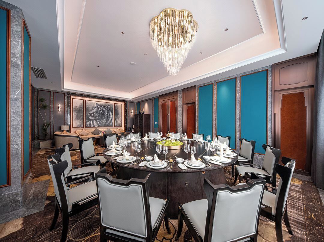 A conference room with a round table set for a meeting, surrounded by chairs, and a large chandelier above.