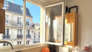 A small kitchen with a window, a sink, and two orange chairs. - Studio Quartier Latin & Seine (Paris)