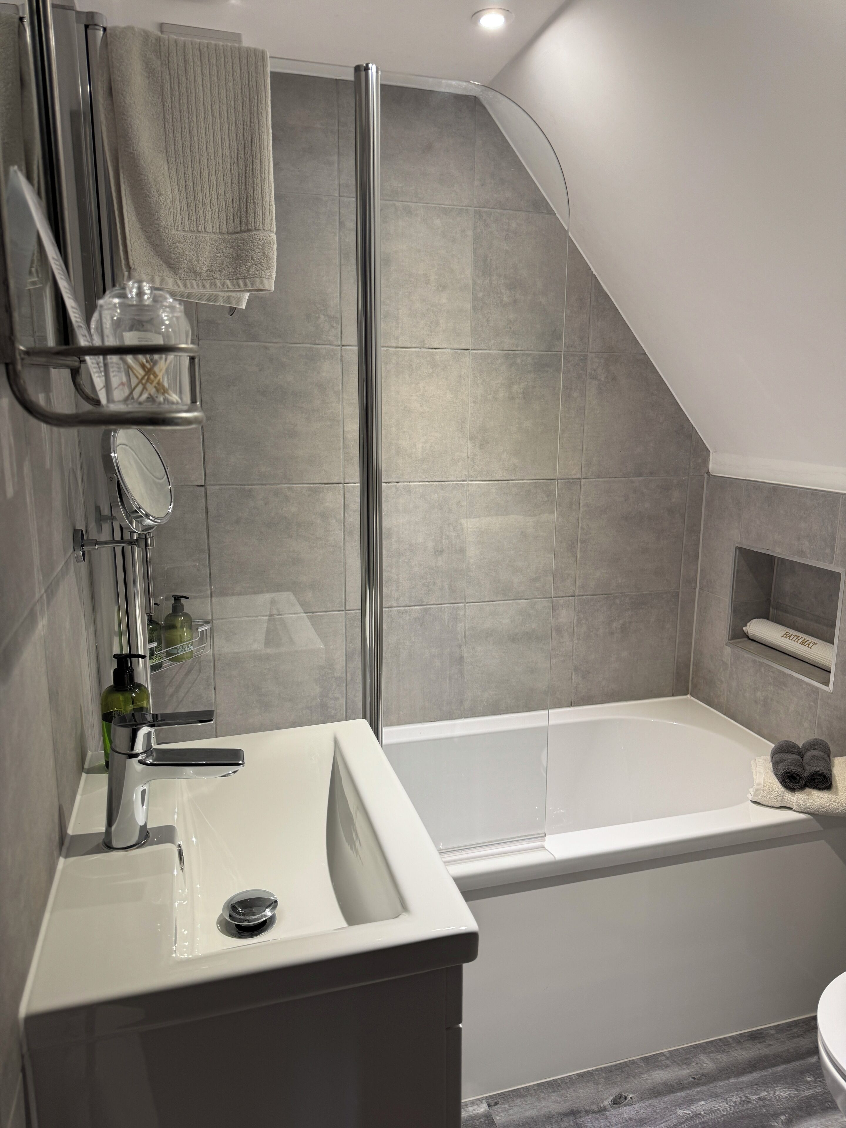 Une salle de bain moderne équipée d’une baignoire, d’une zone de douche et d’un meuble-lavabo avec un évier et un miroir.