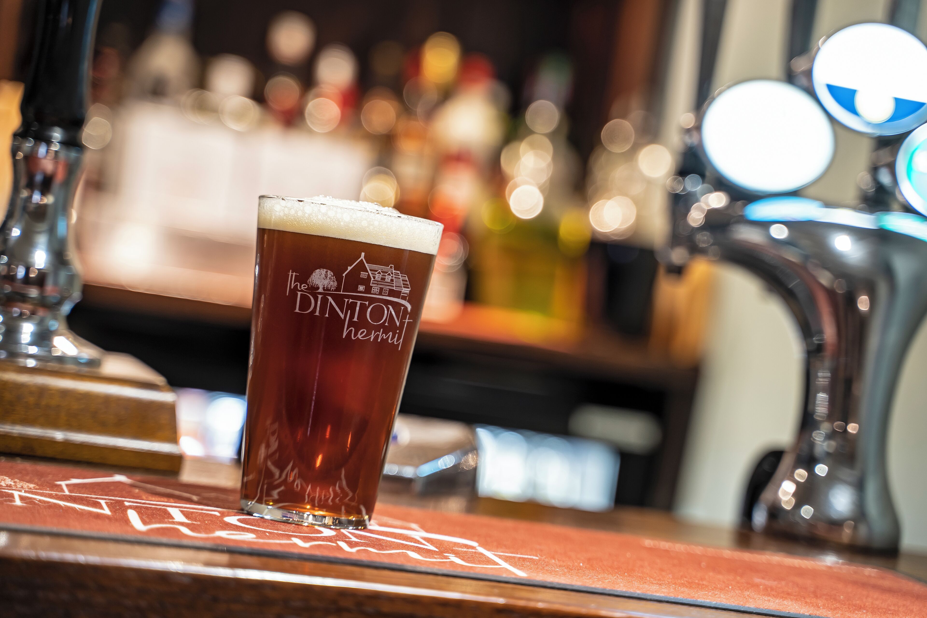 Un verre de bière avec une étiquette posé sur le comptoir d’un bar.