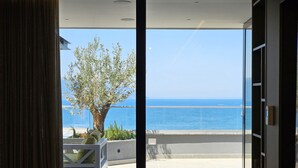An open sliding glass door leading to a balcony with a view of the sea and a tree. - La Terrazza Azzurra (Vlore)