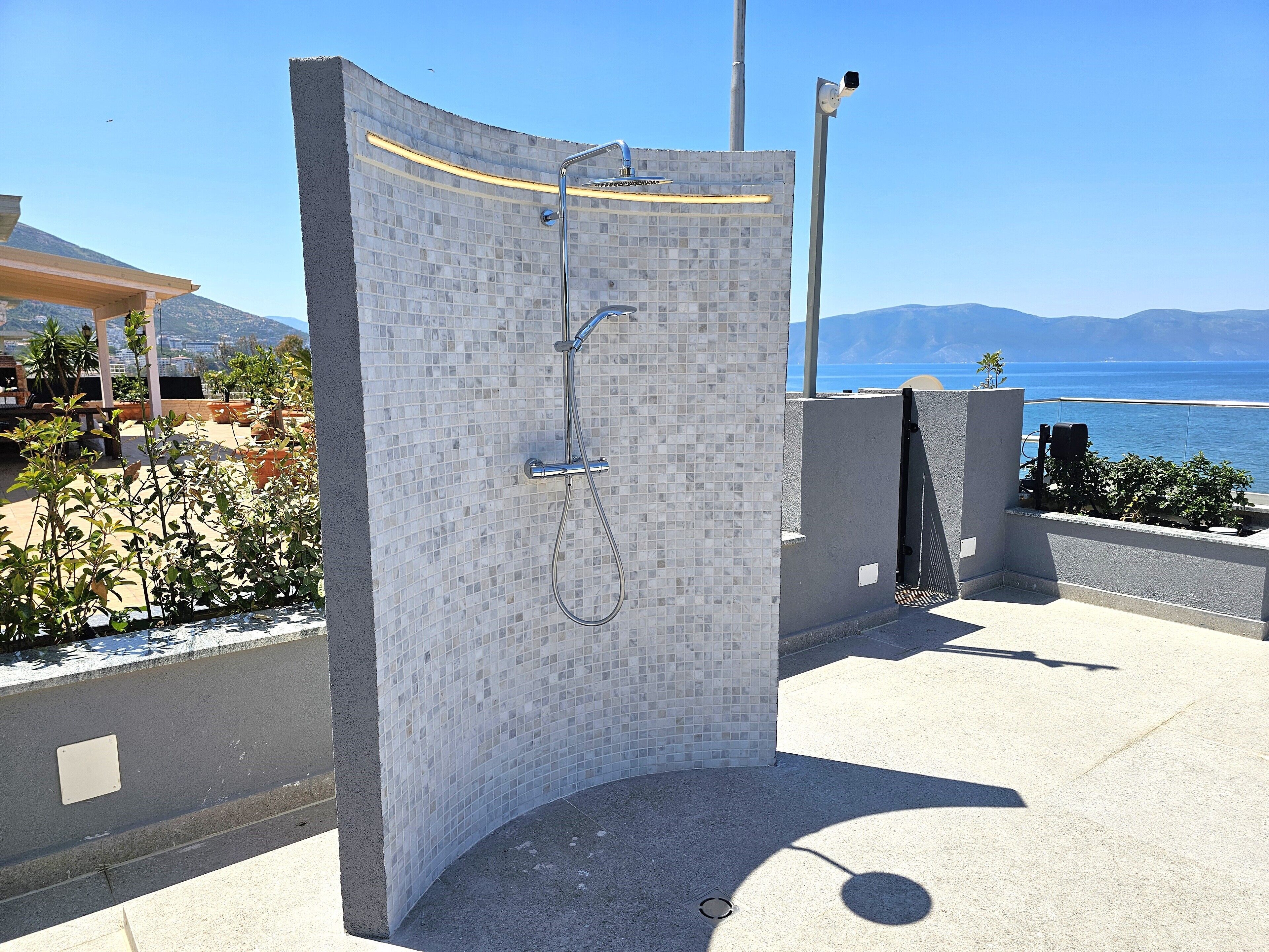 Zona d'aigua amb dutxa tancada per vidre i vista al mar.